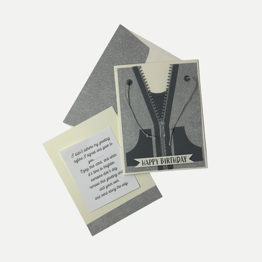 A birthday card set featuring a front card with a black and gray zipper graphic and the words 'HAPPY BIRTHDAY,' a cream insert card with a poem, and gray envelopes, arranged on a light gray background.