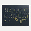 Elegant handmade black birthday card featuring gold foil "Happy Birthday to You" lettering with musical note accents.